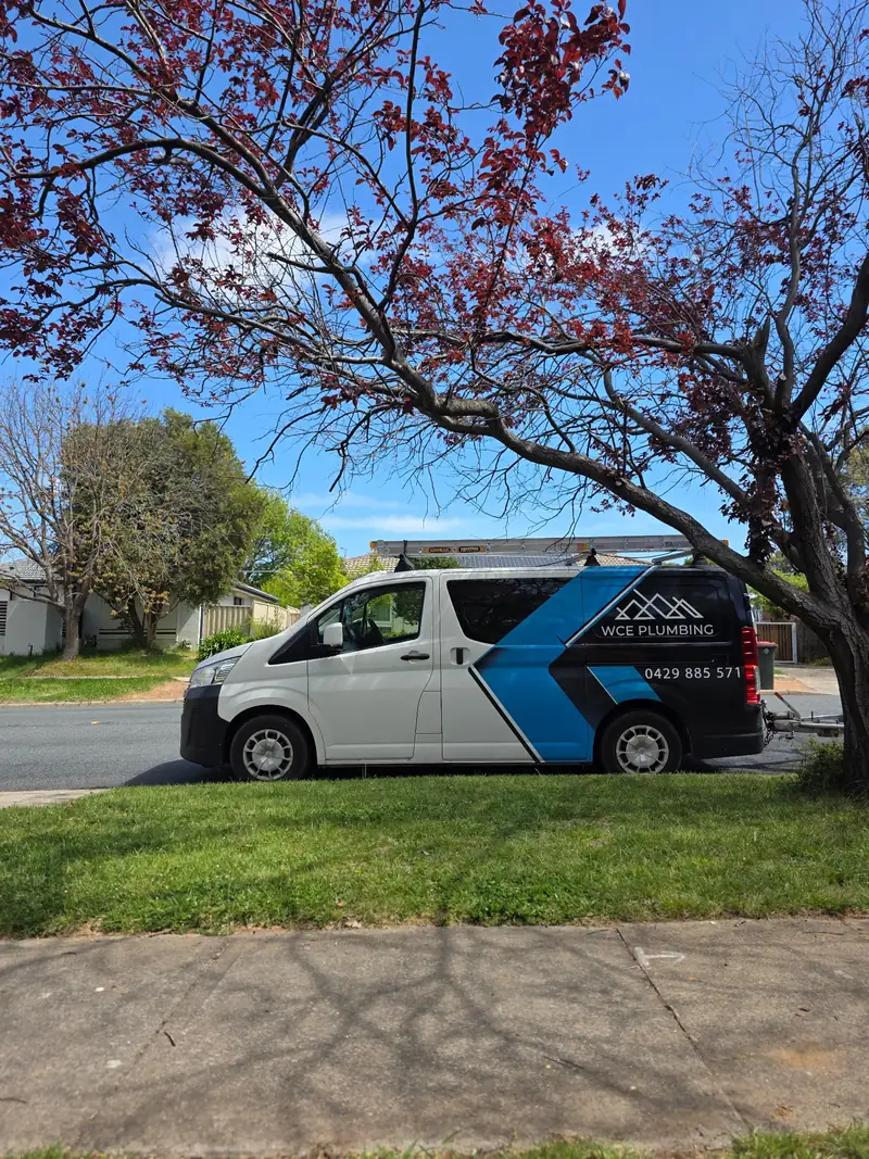 The WCE Plumbing van parked under a flowering tree on a Canberra street.